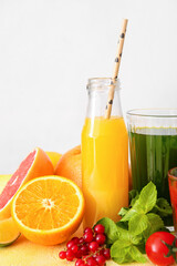 Bottle with healthy juice, fruits and vegetables on light background