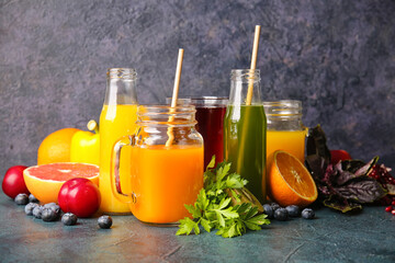 Bottles with healthy juice, fruits and vegetables on dark background