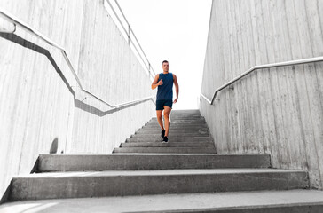Obraz na płótnie Canvas fitness, sport and healthy lifestyle concept - young man running downstairs
