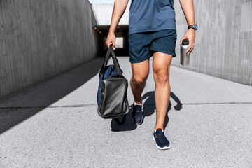 fitness, sport and people concept - sportsman with bag and bottle of water walking outdoors