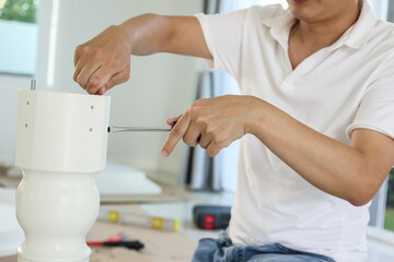 Asian man assembling white table furniture at home