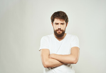 bearded man in a white t-shirt irritated facial expression light background