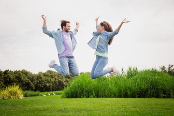 Full size photo of smiling good mood married couple jumping raise hands in victory triumph enjoy...