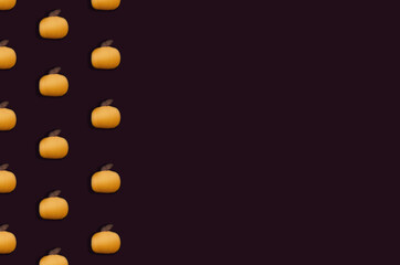 Pattern with orange pumpkins on the dark violet background. Flat lay. 
