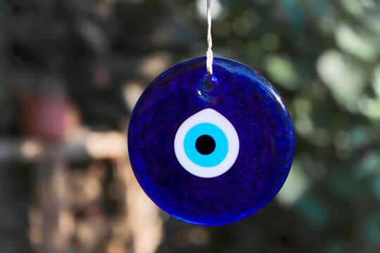 Evil eye bead, Turkiah nazar bead. Blue evil eye beads hanging with a rope from a tree branch. Traditional Evil Eye Amulets.