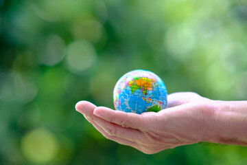 Hand holding globe on green background, ecology, save world