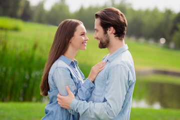 Photo portriat young couple smiling walking in green park looking at each other having date