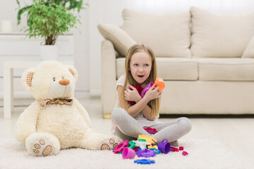 Photo of little girl holding toys on the floor. © Andrii