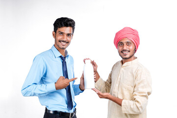 Young indian agronomist giving bottle to farmer on white background.