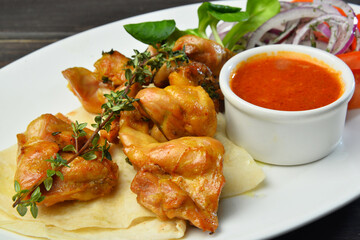 roasted chicken kebab with onion and sauce on a plate