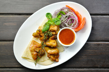 roasted chicken kebab with onion and sauce on a plate