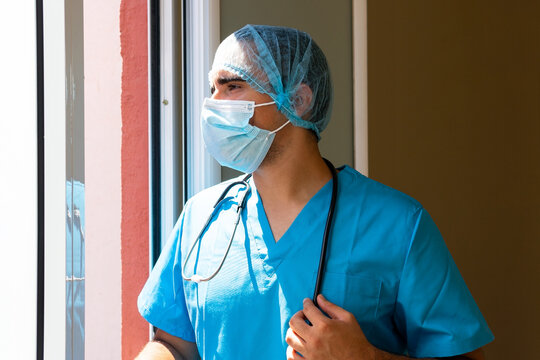 Male doctor standing in hospital with hat and face mask