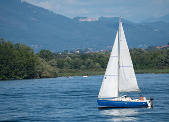blue sailboat sailing on lake Maggiore.Lombardy,italian lakes,Italy.