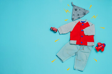 Boys jacket, jeans and hat with toys over blue background