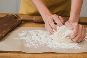 A woman baker or pastry chef kneads the dough. Close-up.