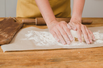 A woman baker or pastry chef kneads the dough. Close-up.