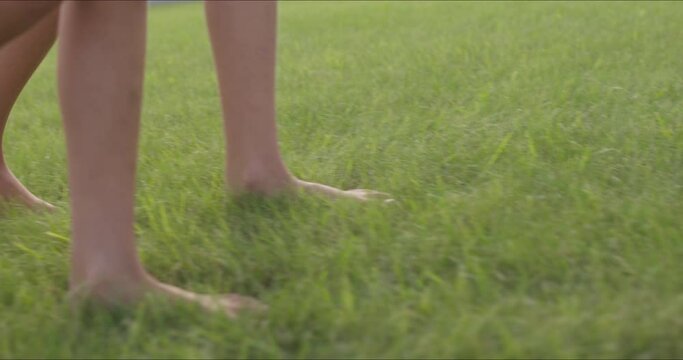 girls walk bare feet on green grass