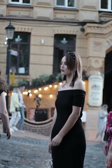 girl in a black short dress on the evening street. against the backdrop of lights, shops.