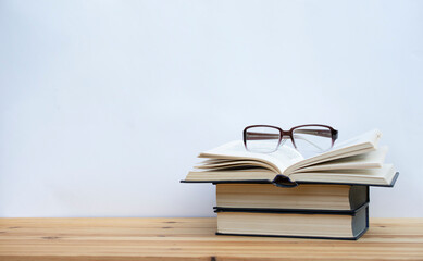 2  books closed and one open book with glasses on white background with free copy space, education