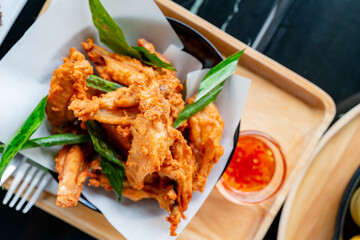 shot from above Several pieces of battered chicken wings are fried until crispy and garnished on a white plate for a beautiful sauce. on the table