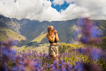 Young tourist woman enjoy view from Gergeti Trinity Church (Tsminda Sameba) in Kazbegi, Georgia. The Church near the village of Gergeti, under Mount Kazbegi in summer. Travel in georgia