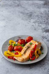 Baked red fish fillet Arctic char on a plate with vegetables close up, delicious hearty healthy dinner
