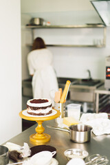 Confectioner girl is preparing a cake biscuit with white cream and chocolate. Cooking cakes.