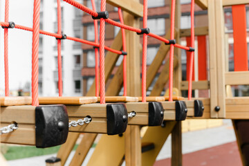 An outdoor colorful playground next to the house. A summer day. Children's playground with rubber floor covering. Close-up, details of a wooden house for children.