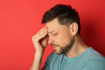 Fototapeta premium Man suffering from terrible migraine on red background
