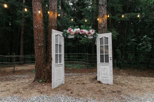 Wooden doors painted white with flowers and green leaves are standing in the forest. wedding registration area.