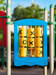 Vertical view of a colorful circular tic-tac-toe children's game with a broken piece in a playground