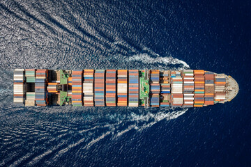 Aerial top down view of a large container carrier ship traveling over blue ocean