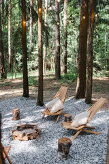 Wooden chairs around the fireplace. Pine forest. Family holidays in the country, fun trips in the fresh air. Rest on a picnic at a camping site.