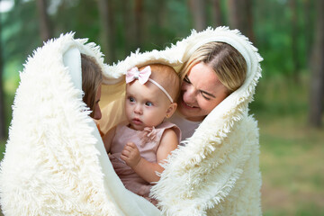 Two women hold a beautiful little girl in their arms.