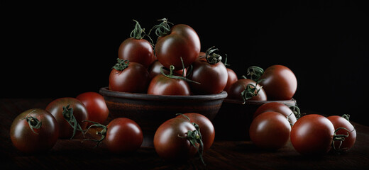 A lot of ripe juicy tomatoes on a black background. Cumato tomatoes.