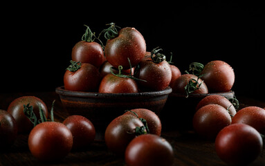A lot of ripe juicy tomatoes on a black background. Cumato tomatoes.