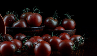 A lot of ripe juicy tomatoes on a black background. Black tomatoes are cumato.