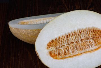 A ripe melon cut in half with seeds on a black background.