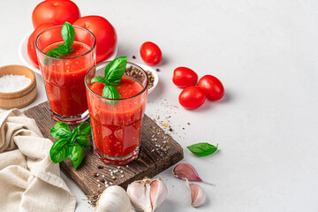Tomato juice with basil and spices on a light background. Side view, space for copying. Vegetable drink.