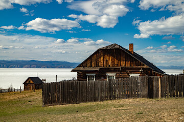 Fototapeta na wymiar An old wooden house surrounded by a wooden fence on the shore of Lake Baikal.