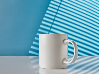 White cup on table on blue background
