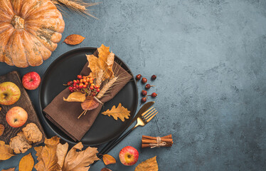 Festive autumn background with cutlery, leaves and pumpkin on a dark background. Top view, copy...