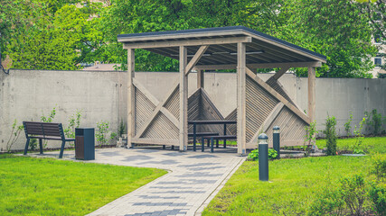 Fototapeta premium Wooden gazebo for relaxing in the yard. Green lawn.
