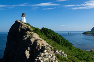 Fototapeta na wymiar old lighthouse on the cliff against blue sky on a sunny dat