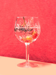 Chill out party concept made of beautiful, antique crystal glass with  cocktail in it. Aronia berries and yellow egg plum garnish. Lovely red velvet and pink background.