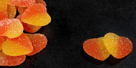 Two heart-shaped sweets next to a lot of sweets. Marmalade candy in the form of a heart.