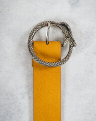 Beautiful yellow leather belt with silver metal buckle in the shape of snake eating itself...