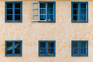 Fototapeta na wymiar Six wooden blue painted windows on plaster wall. Architectural background