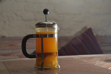 french-press with hot tea in the evening on wooden table