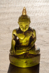 Beautiful backlit yellow green crystal buddha statue on bright wooden background